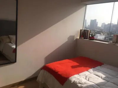 a bedroom with a bed with a red blanket and a window at Precioso cuarto dentro de un apartamento centrico compartido in Lima