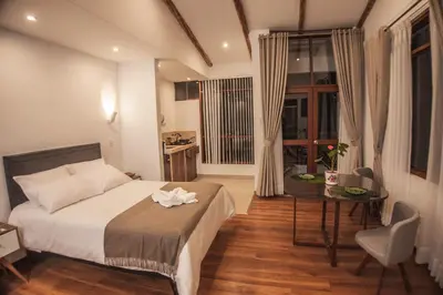 a bedroom with a bed and a table and a kitchen at Florez de la Villa in Huaran