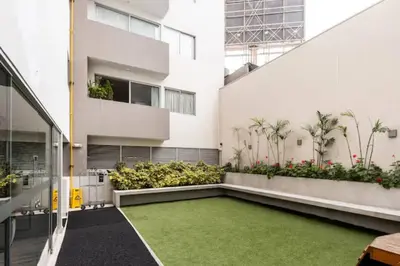 a courtyard of a building with a green lawn at Lindo y Espacioso Departamento muy cerca a Miraflores in Lima