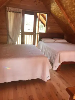 a bedroom with two beds in a wooden cabin at Cabañas - Kobold Haus in Oxapampa