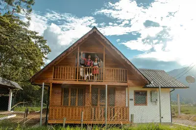 three people standing on the balcony of a house at Cabañas - Kobold Haus in Oxapampa
