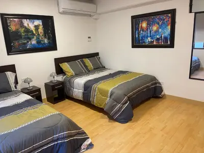 a bedroom with two beds and paintings on the wall at 19 Departamento en el centro de Miraflores in Lima