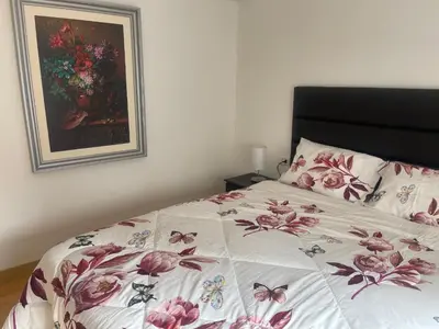 a bedroom with a bed with a floral bedspread and a painting at 13 Nuevo y acogedor departamento en Miraflores in Lima