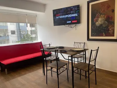 a dining room with a red couch and a table and chairs at 14 Departamento acogedor y nuevo en Miraflores in Lima