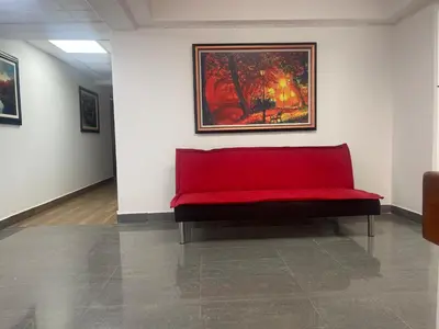 a red bench in a room with a painting on the wall at 15 Acogedor dpto de un ambiente en miraflores in Lima