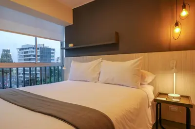 a bedroom with a white bed with a large window at Black by Wynwood House in Lima