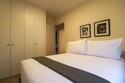 a bedroom with a white bed with two pictures on the wall at Black by Wynwood House in Lima