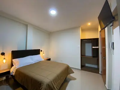 a bedroom with a bed and a flat screen tv at Hotel Alba in Ica