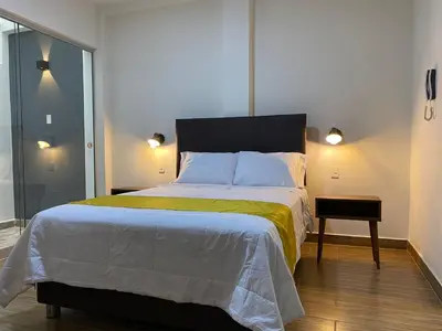 a bedroom with a large bed with a yellow and white blanket at Hotel Alba in Ica