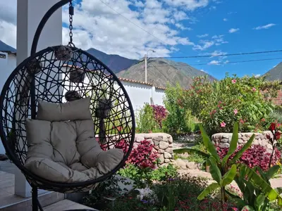 a swinging chair in a garden with flowers and mountains at Flores de la Villa in Huayoccare
