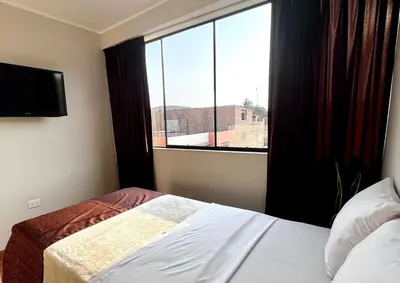 a bedroom with a bed and a large window at COSMOPOLITAN INN in Ventanilla