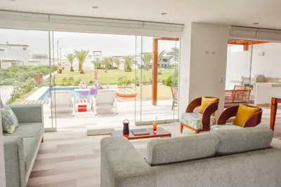 a living room with two couches and a pool at Casa de playa: Disfruta de grandes momentos y del sol todo el año en Paracas in Paracas