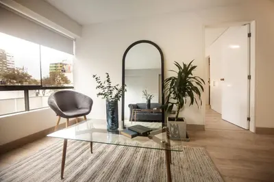 a living room with a glass table and a mirror at San Martin 598 by Wynwood House in Lima