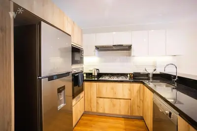 a kitchen with a stainless steel refrigerator and wooden cabinets at Alcanfores 1262 by Wynwood House in Lima
