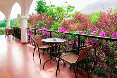a table and chairs on a balcony with flowers at Casa Hotel Mamaluna in Lunahuaná