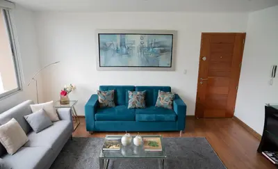 a living room with a blue couch and a table at Apartment in Center of Miraflores in Lima