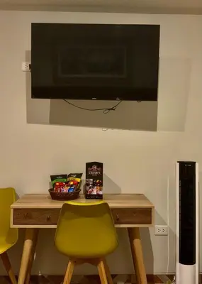 a table with a green chair and a television on a wall at Cesars Hotel Lima in Lima