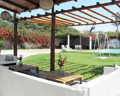 a wooden pergola with two tables in a yard at LAS PALMERAS HOSTAL in Barranca