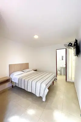 a white bedroom with a bed and a mirror at LAS PALMERAS HOSTAL in Barranca