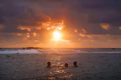 a group of people in the ocean at sunset at VIVEMAR PUNTA HERMOSA - Beach House Lima - Perú in Punta Hermosa