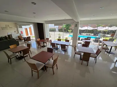 a restaurant with tables and chairs and a pool at Silver Inn Hotel in Cerro Azul