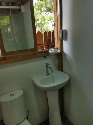 a bathroom with a sink and a toilet and a mirror at Fachwerkhaus zum Hirsch in Oxapampa
