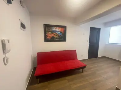 a red bench in a room with a painting on the wall at (21) Depto. nuevo y acogedor en Miraflores in Lima