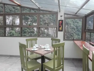 a dining room with a table and chairs and windows at Hotel Pucara Machupicchu in Machu Picchu