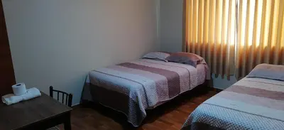 a bedroom with two beds and a table and a window at Catalina Huanca Resort in San Jerónimo