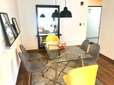a dining room with a glass table and yellow chairs at Hermoso apartamento con piscina Miraflores- Canvas in Lima