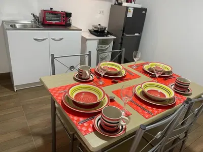 a table with red and yellow plates and wine glasses at (28) Acogedor dpto. Miraflores in Lima