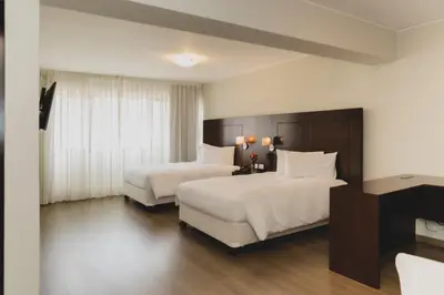 a hotel room with two beds and a desk at ARTE HOTEL Lima in Lima