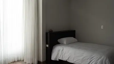 a bedroom with a bed and a window with white curtains at LIMA HOST in Lima