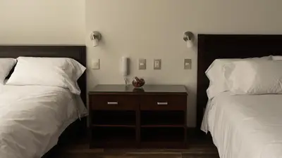 a bedroom with two beds and a wooden nightstand between them at LIMA HOST in Lima