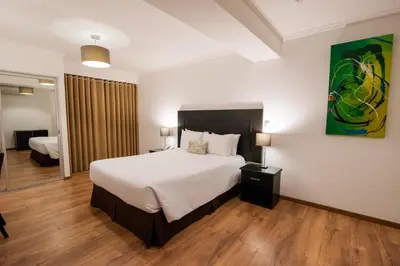 a bedroom with a large white bed and a room at El Polo Hotel & Suites in Lima