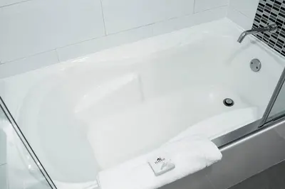 a white bath tub with a towel on it at El Polo Hotel & Suites in Lima