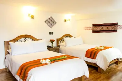 two beds in a hotel room with a cat laying on the bed at Casa San Blas Cusco Boutique Hotel in Cusco