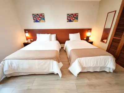 two beds in a hotel room with white sheets at Hotel Las Palmas in Lima