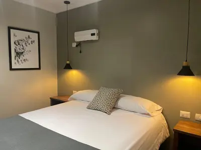 a bedroom with a white bed with two tables and two lights at CASA MONTES PARDO in Cusco