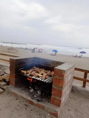 a brick barbecue grill on the beach with people on the beach at Arica Surf & Beach House in Arica