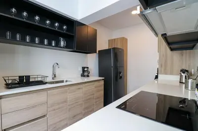 a kitchen with a black refrigerator and wooden cabinets at Actual by Wynwood House in Lima