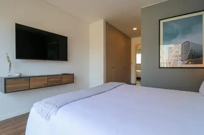a bedroom with a white bed and a flat screen tv at Actual by Wynwood House in Lima