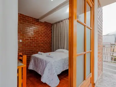 a bedroom with a bed and a brick wall at Las Yungas Hospedaje in Oxapampa