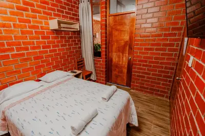 a red brick room with a bed with towels on it at Las Yungas Hospedaje in Oxapampa