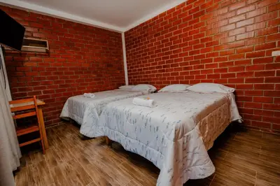 two beds in a room with a brick wall at Las Yungas Hospedaje in Oxapampa