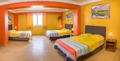 a yellow room with two beds in it at Hotel Savilayo in Ica
