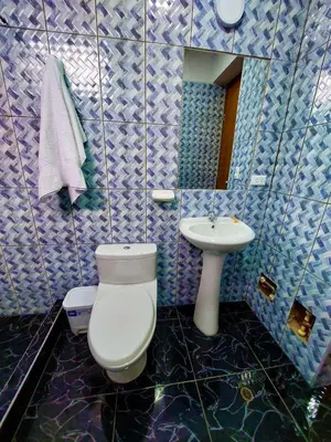 a blue tiled bathroom with a toilet and a sink at Kasanty House in Paracas