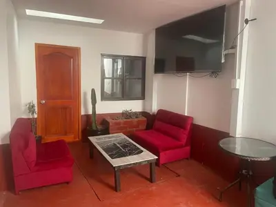 a living room with two red chairs and a table at Mundo Viajero Saphy in Cusco