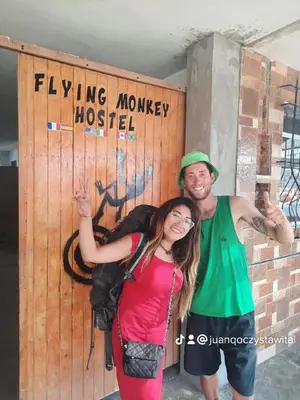 a man and a woman standing in front of a wooden door at flying monkey hostel in Nazca