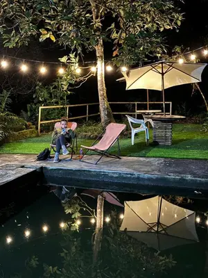 a woman sitting in a chair next to a pool at night at la casa de mamá in Huayopata